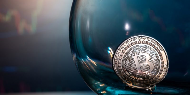 Crypto-Markt Update KW 13 – Bitcoin-Münze in transparenter Glaskugel vor unscharfem Kurschart-Hintergrund
