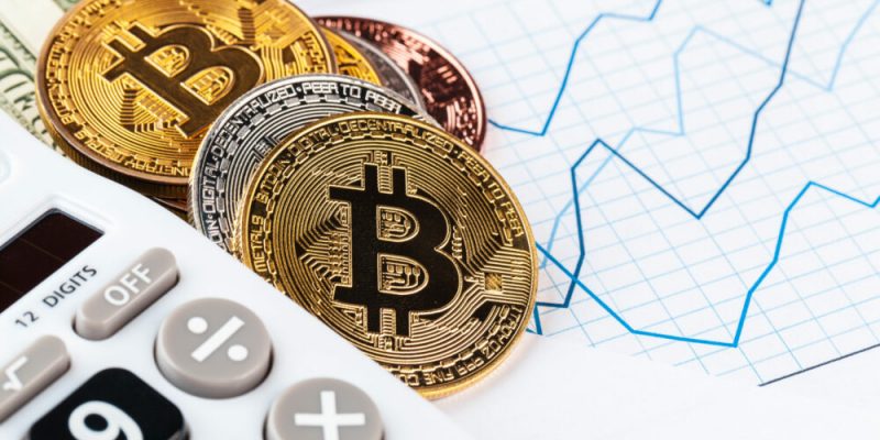 Bitcoin-Münzen und Taschenrechner auf einem Finanzdiagramm zur Bitcoin Marktkapitalisierung.
